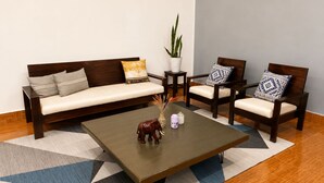 Una sala de estar con sofá, dos sillones, una mesita de centro y una planta en maceta.