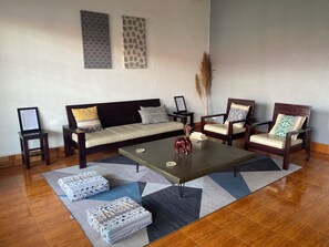 Een woonkamer met een bank, twee fauteuils, een salontafel en een vloerkleed.
