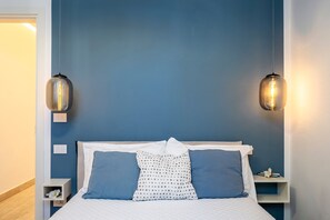 A bedroom with a bed, two bedside tables, and two wall-mounted lamps.