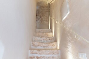 Un escalier avec des marches en pierre et un mur blanc.