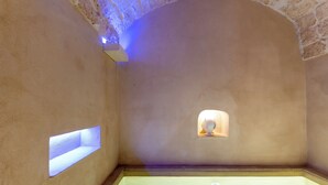 Une salle de spa avec une baignoire, une petite fenêtre et un mur en pierre.