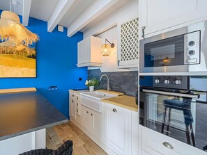 Eine moderne Küche mit weißen Schränken, einer blauen Akzentwand, einer großen Kochinsel und einem Einbauofen.