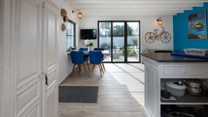 A dining area with a table and chairs, a television, and a view of the outdoors.