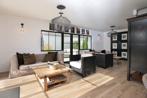 A modern living room with a sofa, armchairs, a coffee table, and a bookshelf.