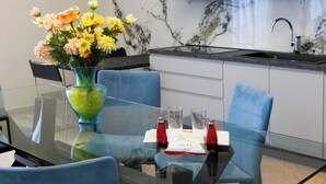 Ein moderner Essbereich mit einem Glastisch, blauen Stühlen und einer Blumenvase.