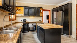 A modern kitchen with granite countertops, stainless steel appliances, and dark cabinetry. - Villa 'Tramuntana' with Sea View, Wi-Fi and Air Conditioning (Costa d'en Blanes)