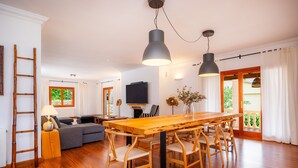 A modern living room with a wooden dining table, two chairs, a sofa, a TV, and a fireplace. - Villa 'Tramuntana' with Sea View, Wi-Fi and Air Conditioning (Costa d'en Blanes)