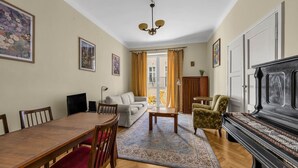 A living room with a dining table, sofa, armchair, and a grand piano. - Śródmieście Apt -Balcony, Workspace - by Rentujemy (Warszawa)