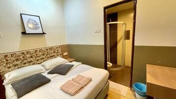 Habitación de hotel con cama, ducha y una pequeña mesa con una silla.