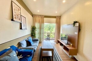 Ein modernes Wohnzimmer mit Sofa, Couchtisch, Fernseher und einem Balkon mit Aussicht.
