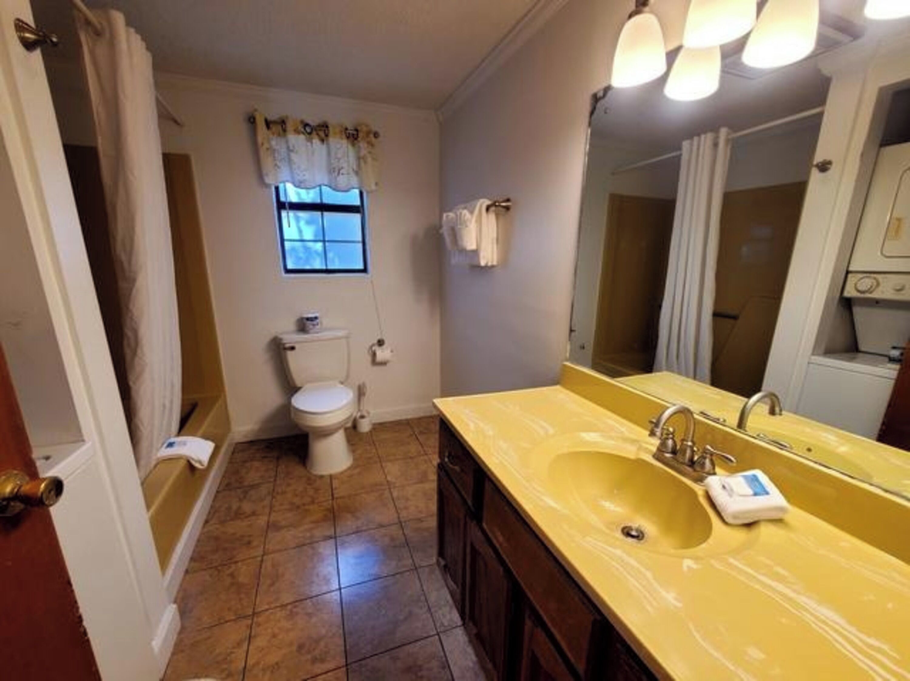 A bathroom with a toilet, sink, and mirror.