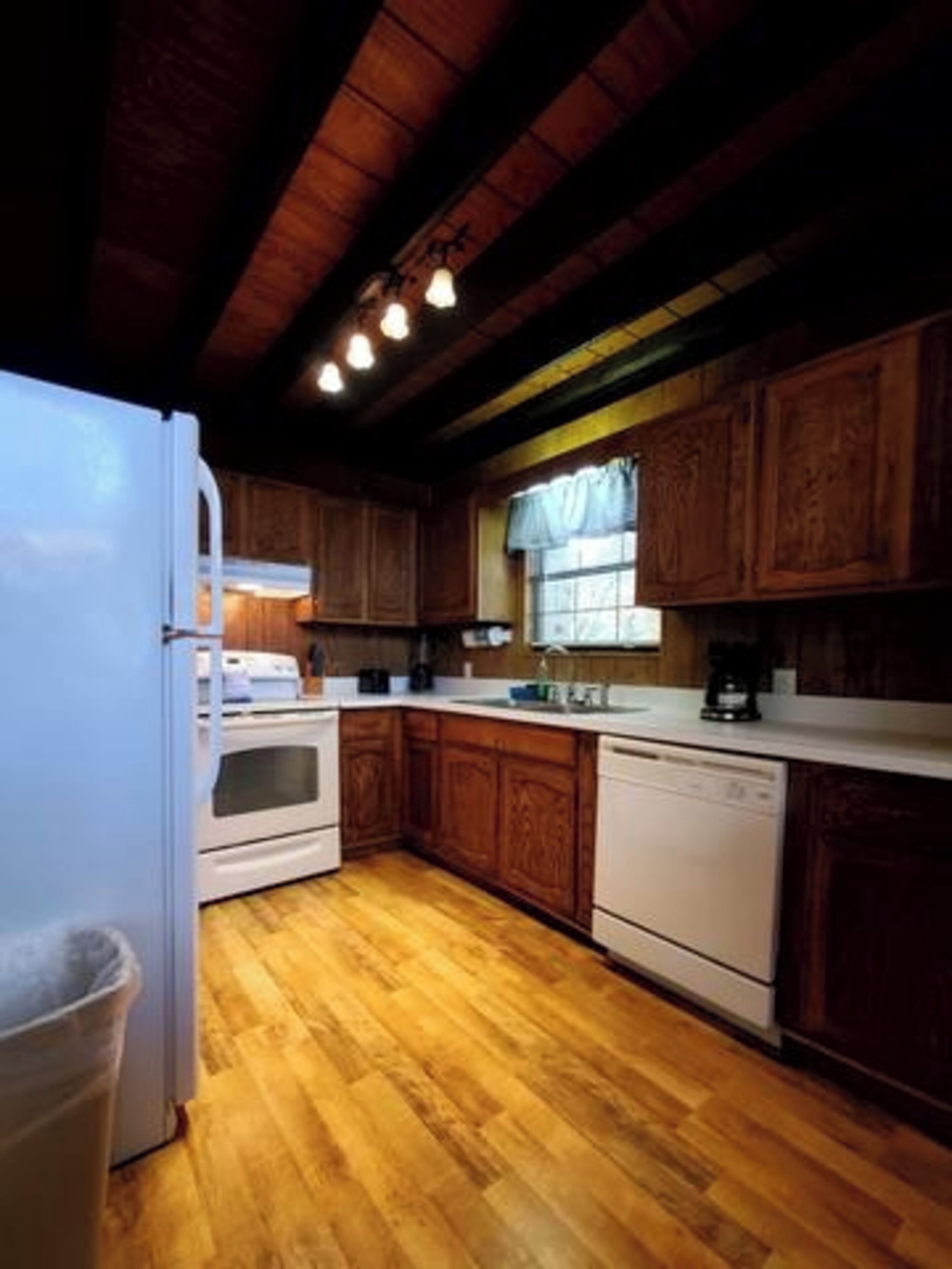 A kitchen with wooden cabinets, a white refrigerator, an oven, and a dishwasher.