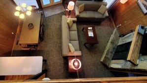Una habitación espaciosa con techos altos, un sofá, una mesa de centro y una chimenea.