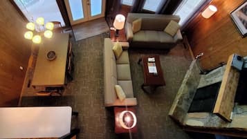 A high-ceilinged room with a sofa, a coffee table, and a fireplace.