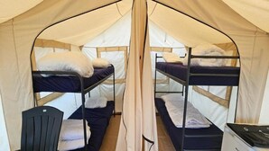 A tent with two bunk beds, a chair, and a small refrigerator. - Nature Escape Tent at Val de Wanne (Trois-Ponts)