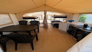 A tent with a dining table and chairs, a kitchenette, and a sleeping area. - Nature Escape Tent at Val de Wanne (Trois-Ponts)