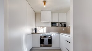 A modern kitchen with white cabinetry, a built-in oven, a microwave, and a coffee maker.
