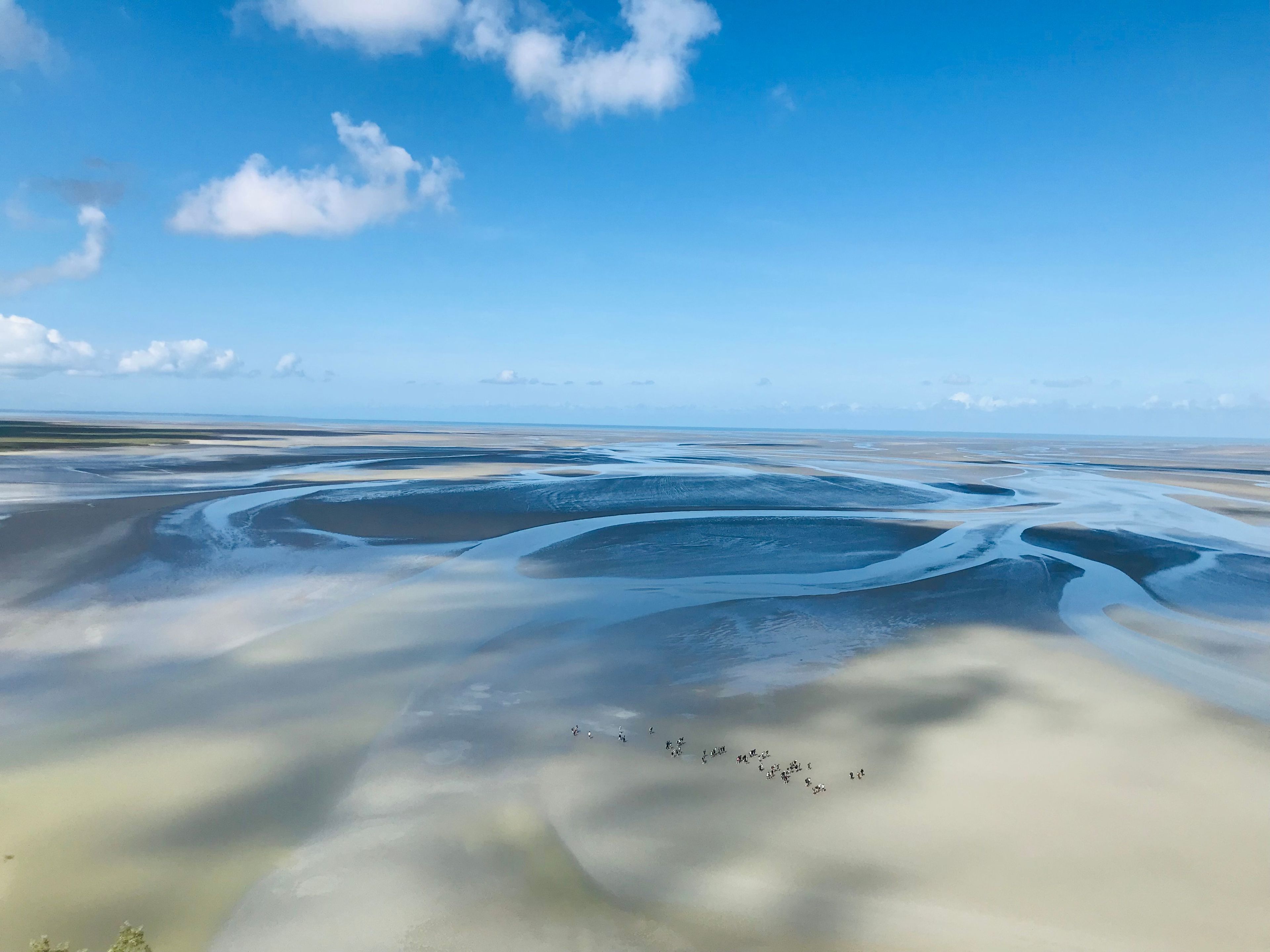 Weite Landschaft mit welligem Gelände und blauem Himmel.