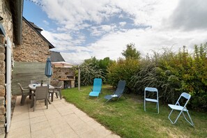 Una casa de piedra con un patio, mobiliario exterior y un jardín.