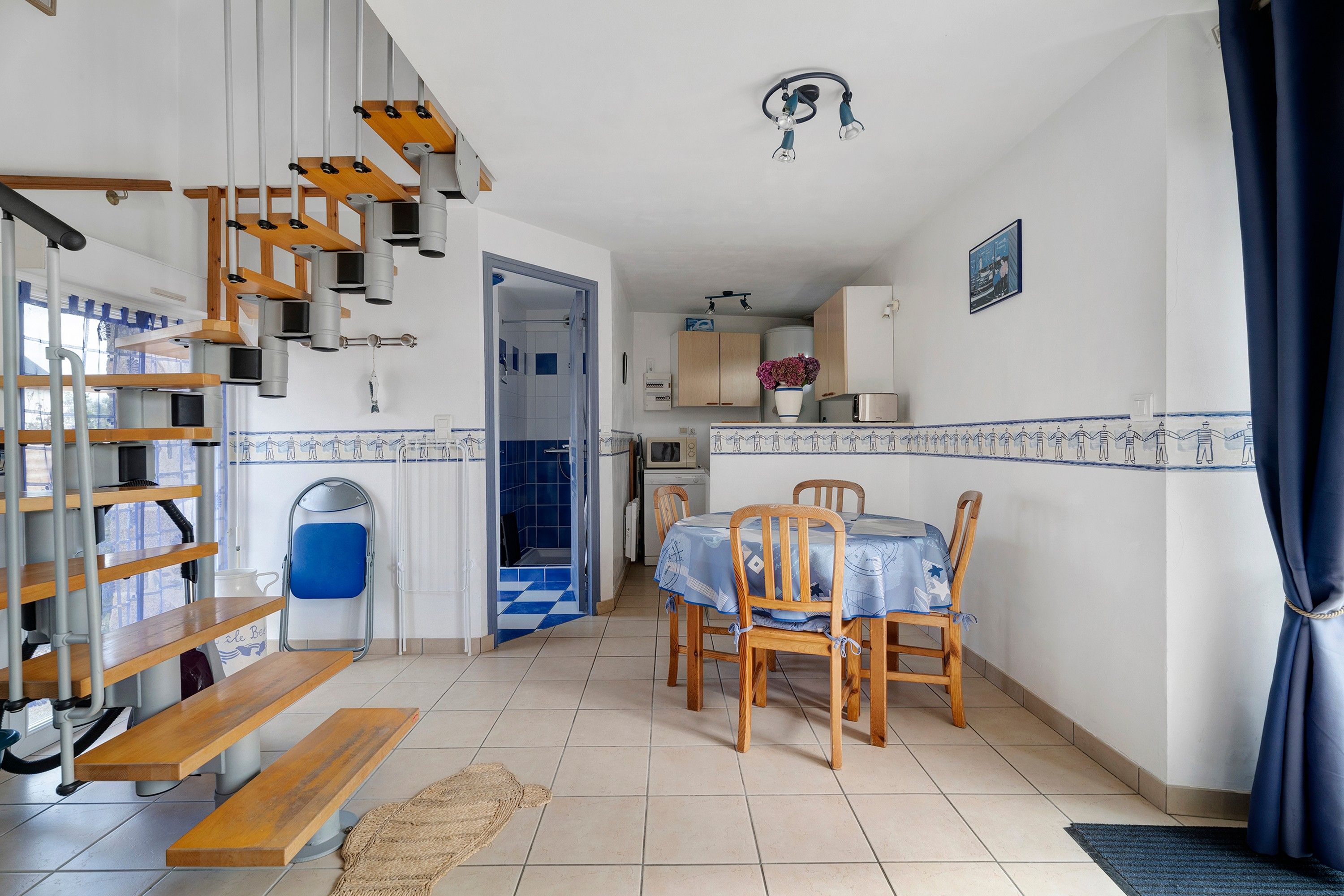 Una cocina compacta con comedor, una escalera y ducha.