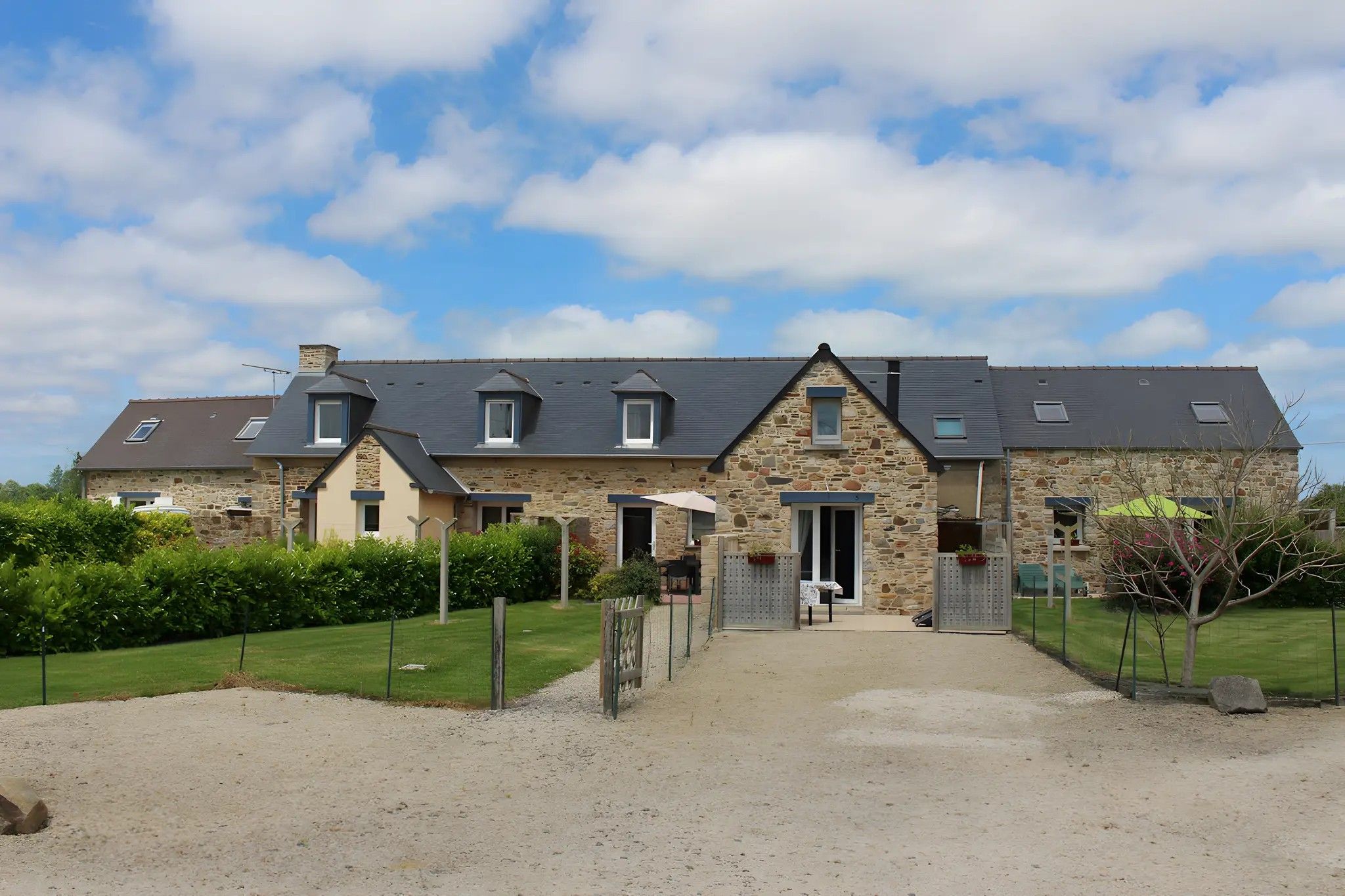A stone building with multiple windows and a gravel driveway.