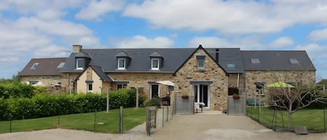 Un bâtiment en pierre doté de nombreuses fenêtres et d’une allée gravillonnée.