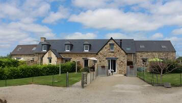 A stone building with a gravel driveway and a fenced yard.