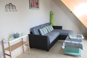 A modern living room with a sectional sofa, a small table, a console table, and a green curtain.
