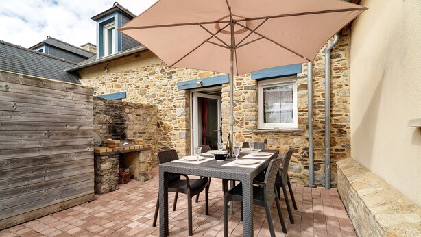 A patio with a table set for dining, stone walls, and a wooden fence.