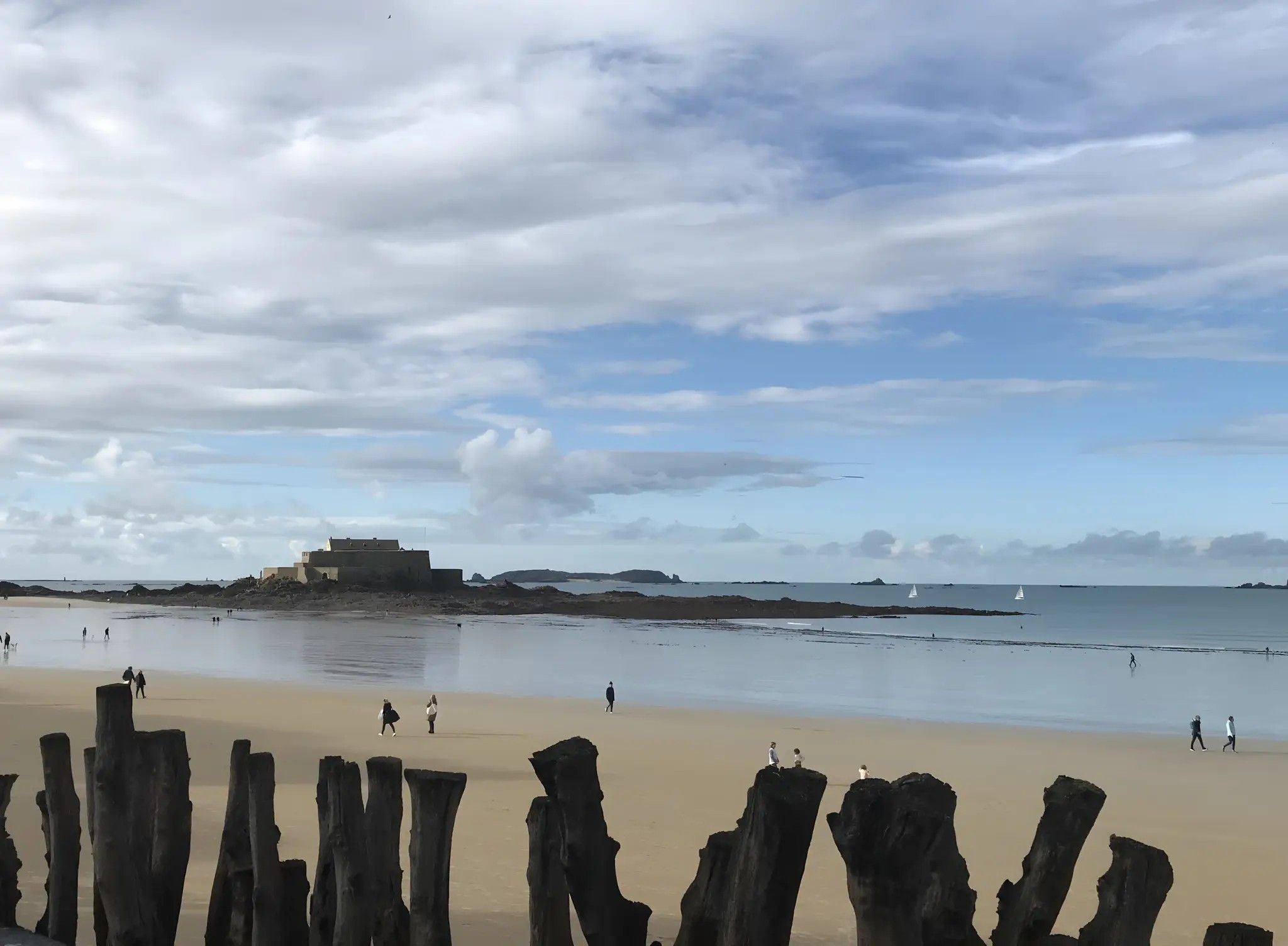 A beach with a historic fort and rocky outcrops.