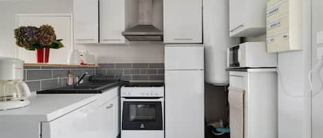 Une cuisine moderne avec des meubles blancs, un lave-vaisselle Bosch, un four Indesit et un four à micro-ondes Siemens.