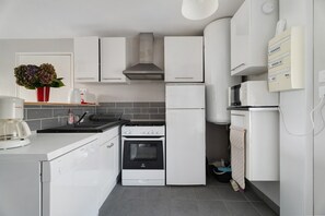 Cocina moderna con armarios blancos, lavavajillas Bosch, horno Indesit y microondas Siemens.