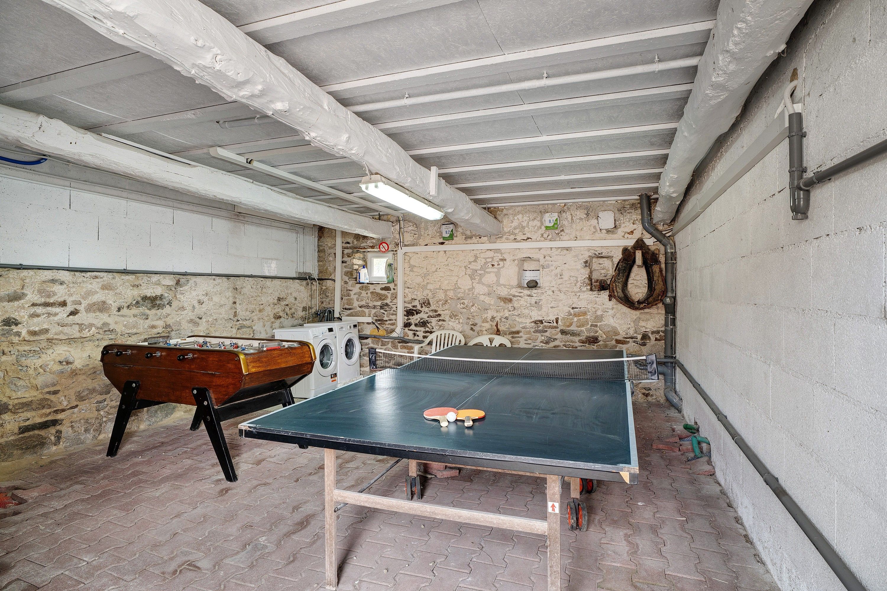 Quarto com mesa de pingue-pongue, mesa de futebol e máquina de lavar.