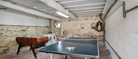 Quarto com mesa de pingue-pongue, mesa de futebol e máquina de lavar.