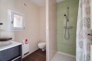 A bathroom with a toilet, a sink, and a shower area.