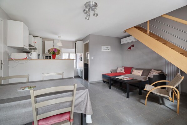 A compact living space with a dining area, kitchenette, and a staircase.