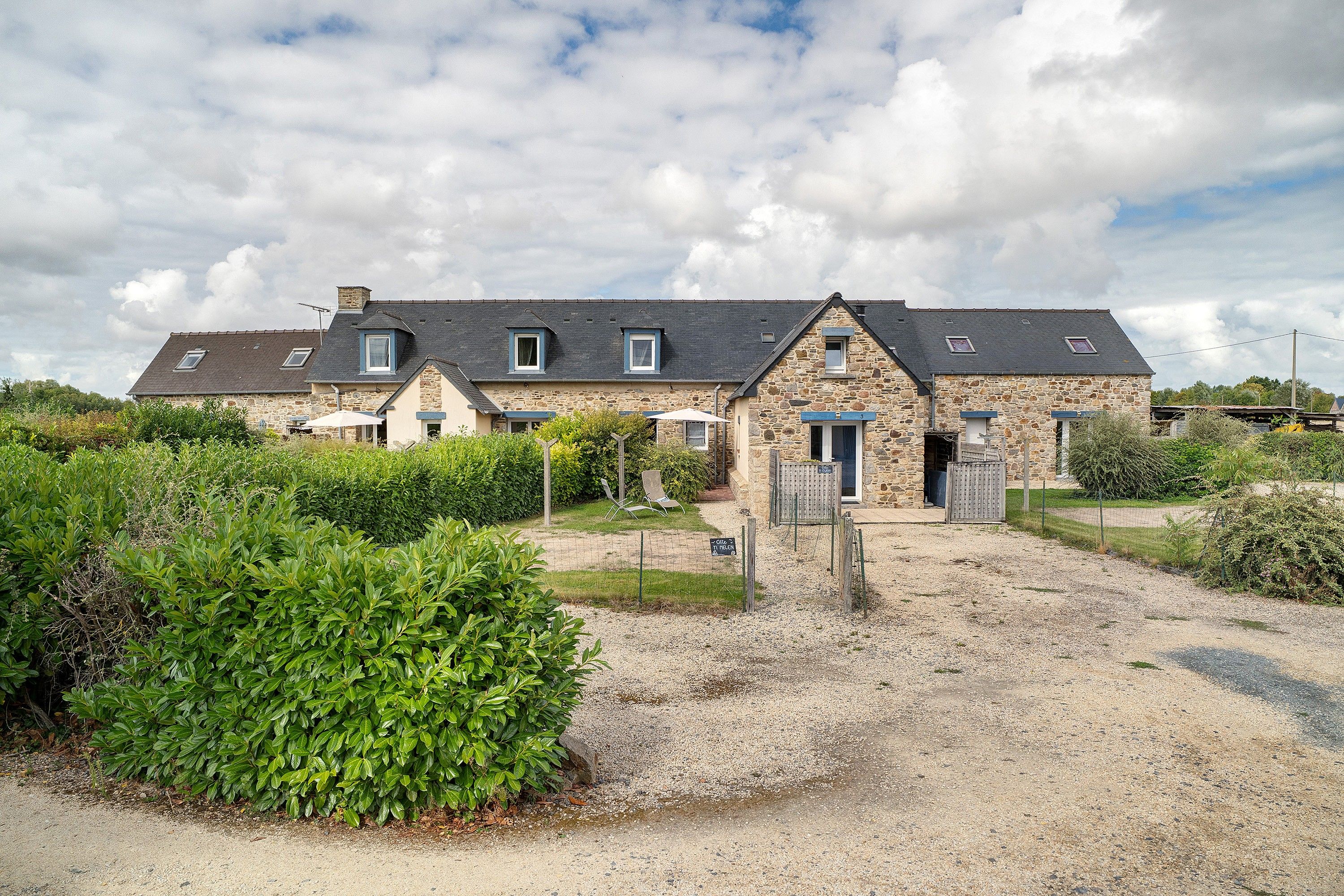 A stone building with multiple windows and a gravel driveway.