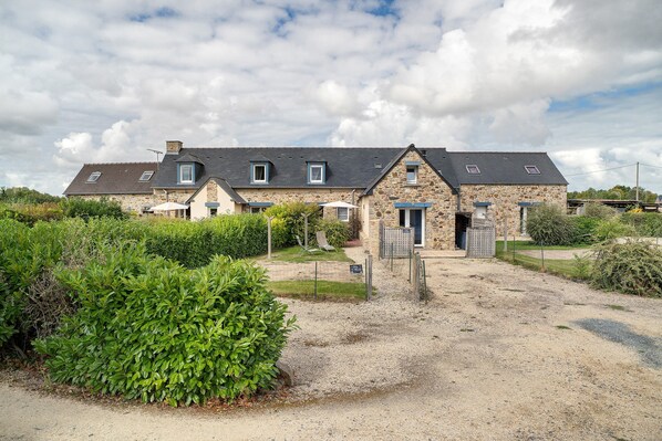 A stone building with multiple windows and a gravel driveway.