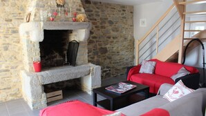 Una chimenea de piedra con un banco, un sofá rojo, un sofá gris y una escalera.