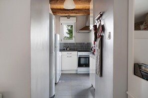 Una cocina estrecha con armarios blancos, una estufa y un ventanal.