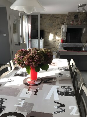 A dining table with a vase of flowers, a modern lamp, and a stone wall in the background.