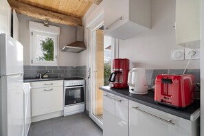 A kitchen with white cabinetry, a stove, a coffee maker, and a toaster.