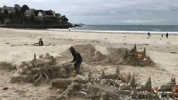 Una playa arenosa con un castillo de arena grande y otra estructura que se asemeja a un castillo.