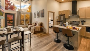 Una cocina moderna con armarios de madera, una isla central con taburetes de bar y una zona de comedor con sofá y mesa de centro.