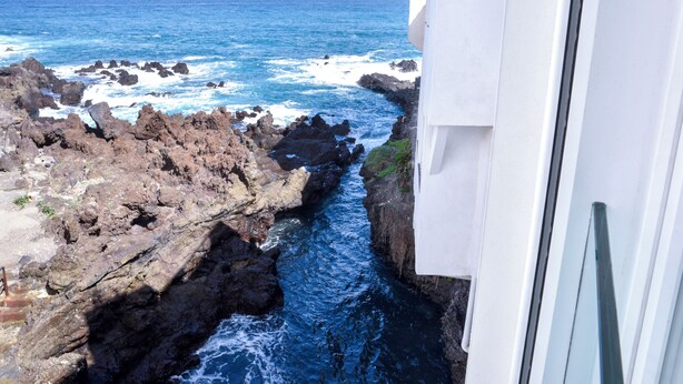 A coastal view with rocky terrain and a narrow water channel.