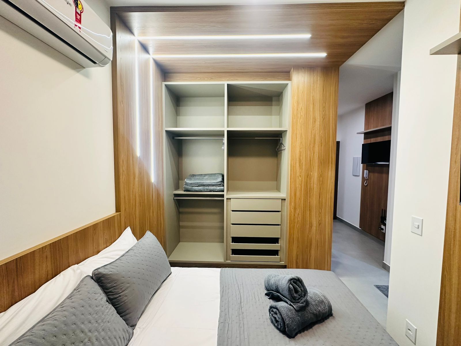 A bedroom with a bed, a wooden wardrobe, and a built-in closet.