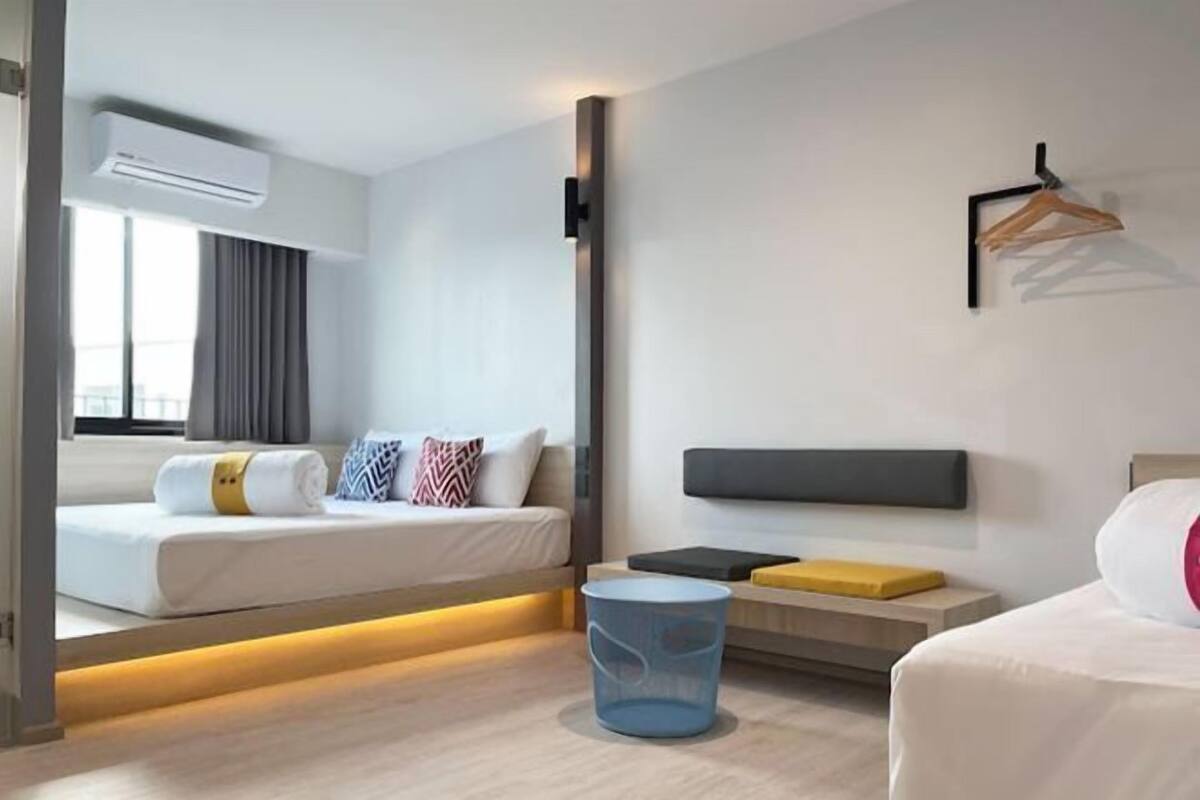 Une chambre d’hôtel moderne équipée d’un lit, d’une table de chevet et d’un climatiseur fixé au mur.