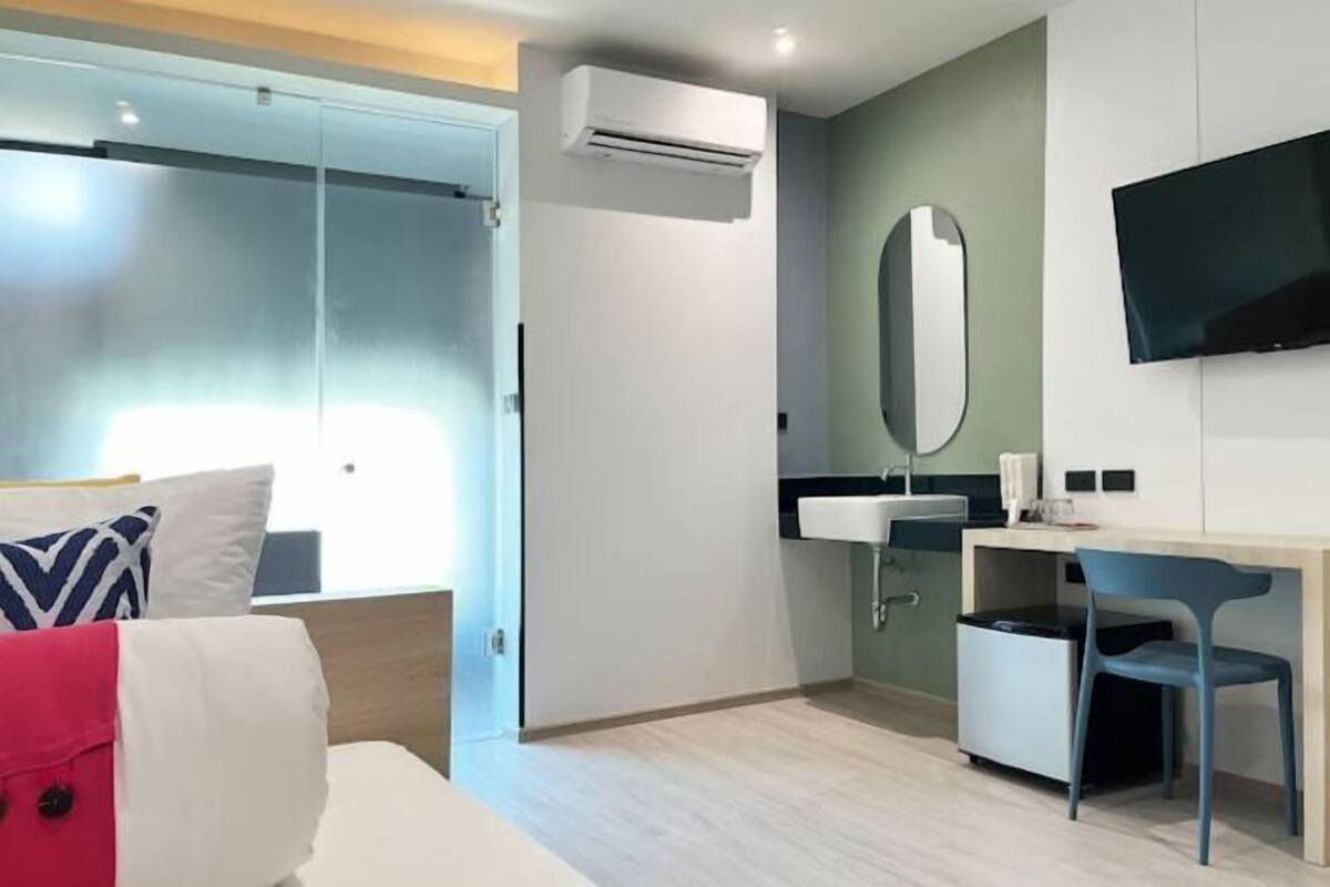 Une chambre d’hôtel moderne équipée d’un lit, d’un bureau, d’une chaise, d’une télévision et d’un appareil de climatisation.