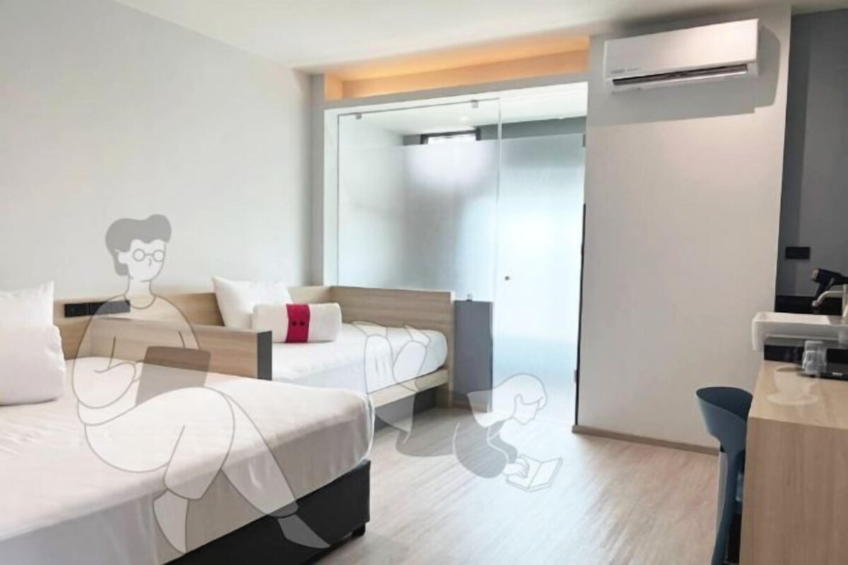 A modern hotel room with two beds, a desk, and a shower area.
