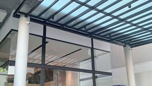 Un interior moderno con fachada de vidrio, vigas de metal y estructura de techo visible.
